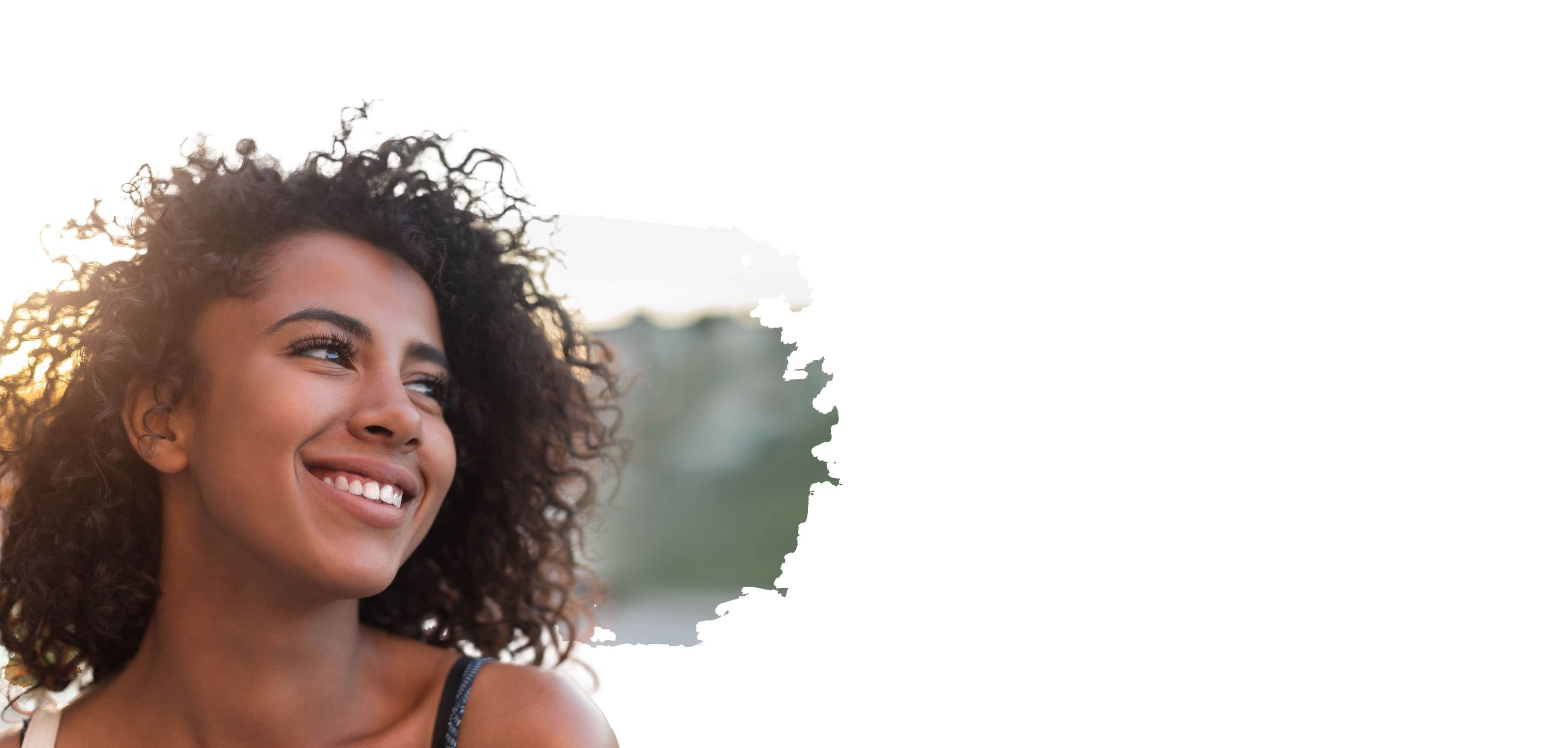 Woman with curly hair smiling and looking off to the side